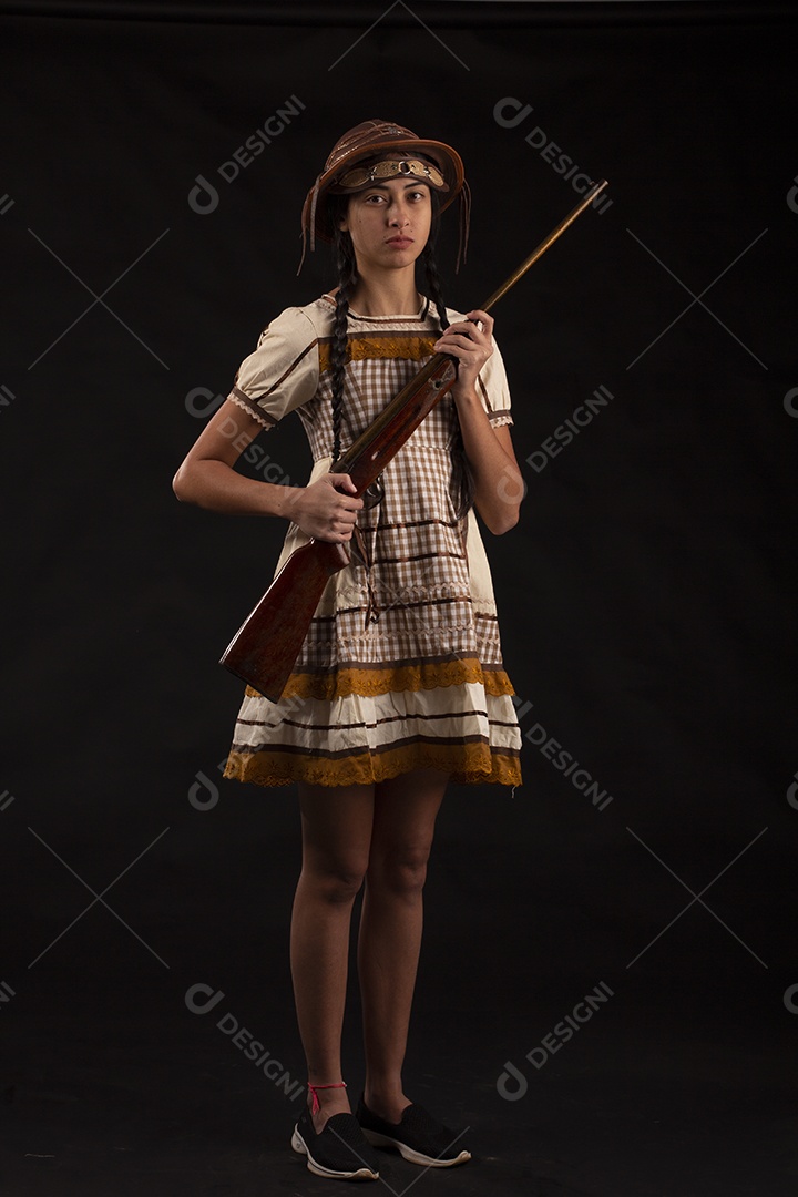 Jovem com trajes típico de festa junina vestido chapéu de couro segurando espingarda