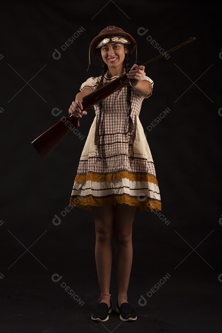 Jovem com trajes típico de festa junina vestido chapéu de couro segurando espingarda