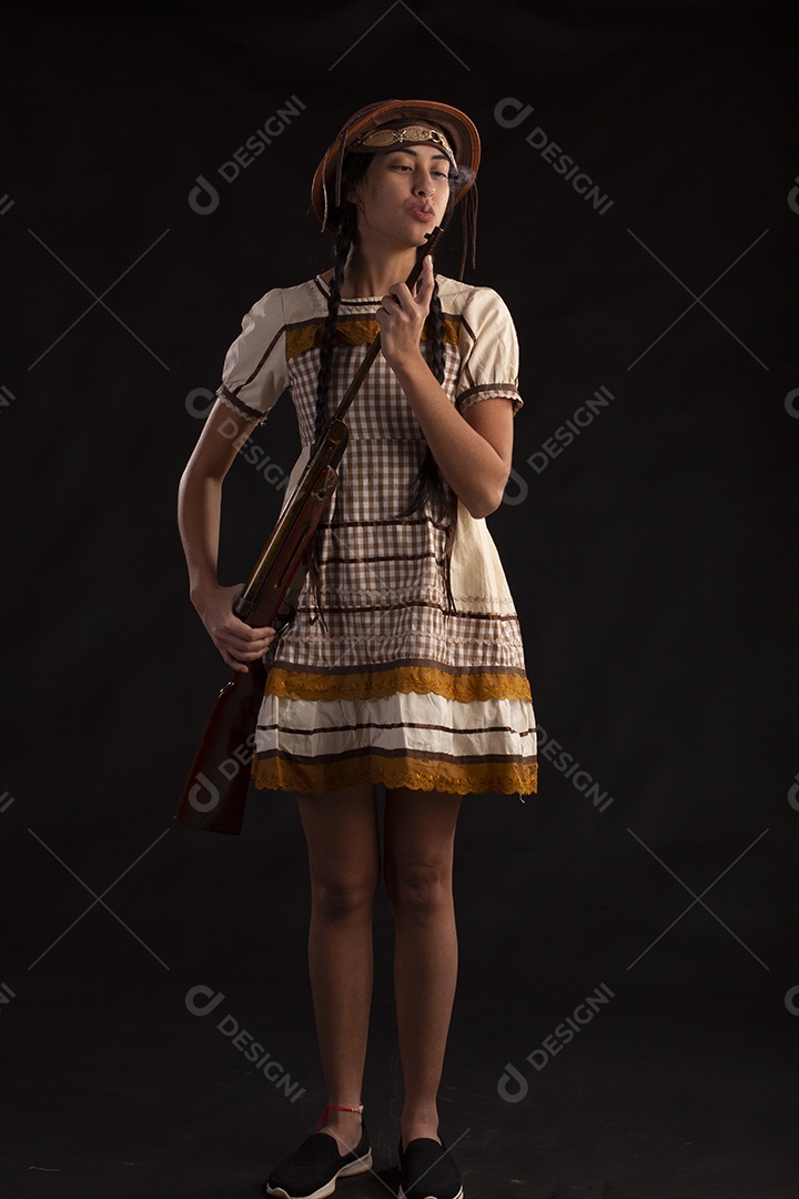 Jovem com trajes típico de festa junina vestido chapéu de couro segurando espingarda