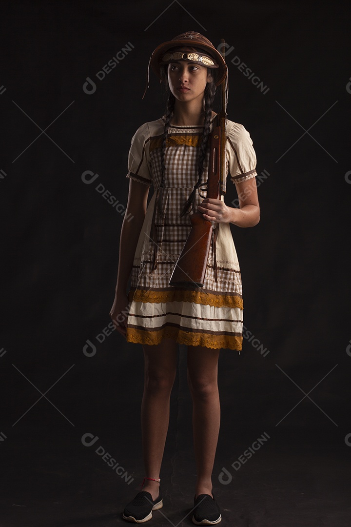 Jovem com trajes típico de festa junina vestido chapéu de couro segurando espingarda