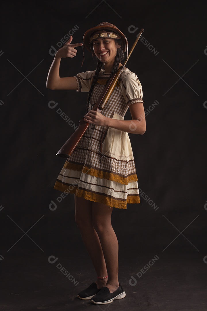 Jovem com trajes típico de festa junina vestido chapéu de couro segurando espingarda