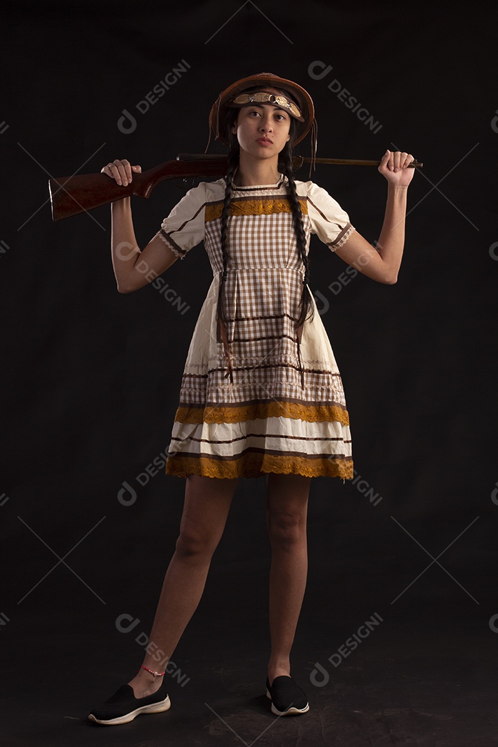 Jovem com trajes típico de festa junina vestido chapéu de couro segurando espingarda