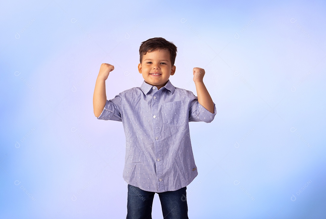 Criança do sexo masculino em foto de estúdio com fundo azul vestindo camisa e jeans