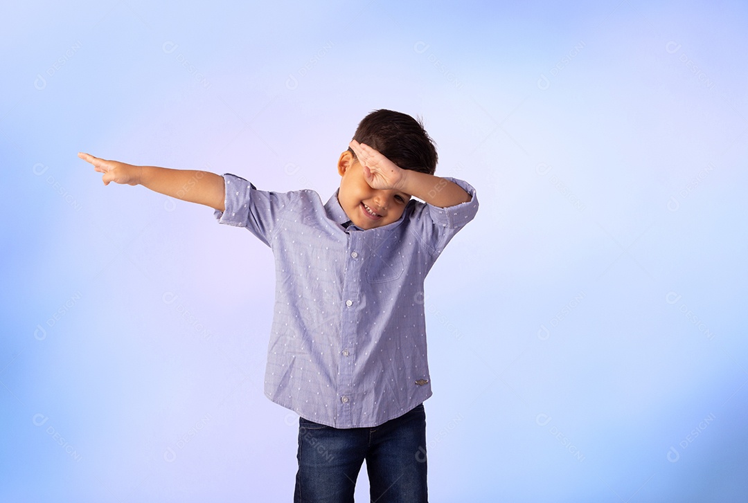 Criança do sexo masculino em foto de estúdio com fundo azul vestindo camisa e jeans