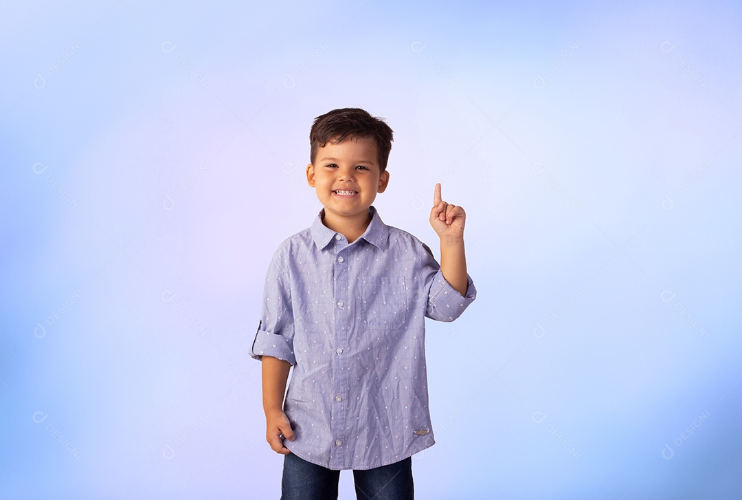 Criança do sexo masculino em foto de estúdio com fundo azul vestindo camisa e jeans