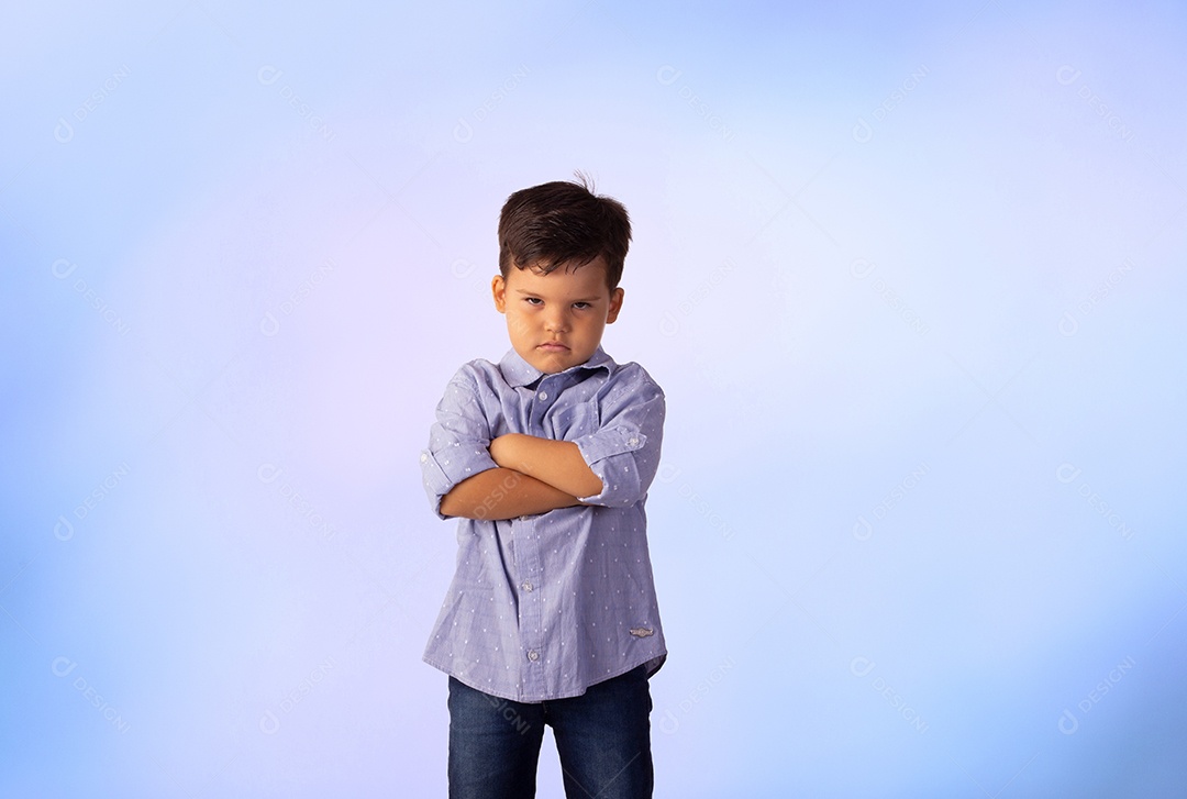 Criança do sexo masculino em foto de estúdio com fundo azul vestindo camisa e jeans