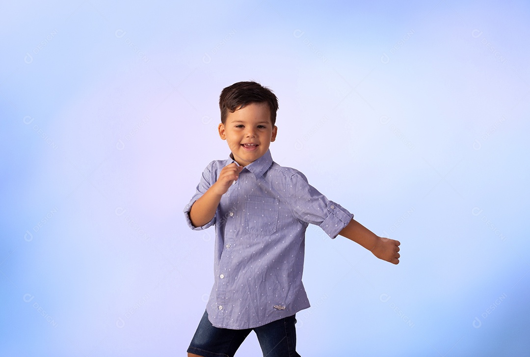 Criança do sexo masculino em foto de estúdio com fundo azul vestindo camisa e jeans