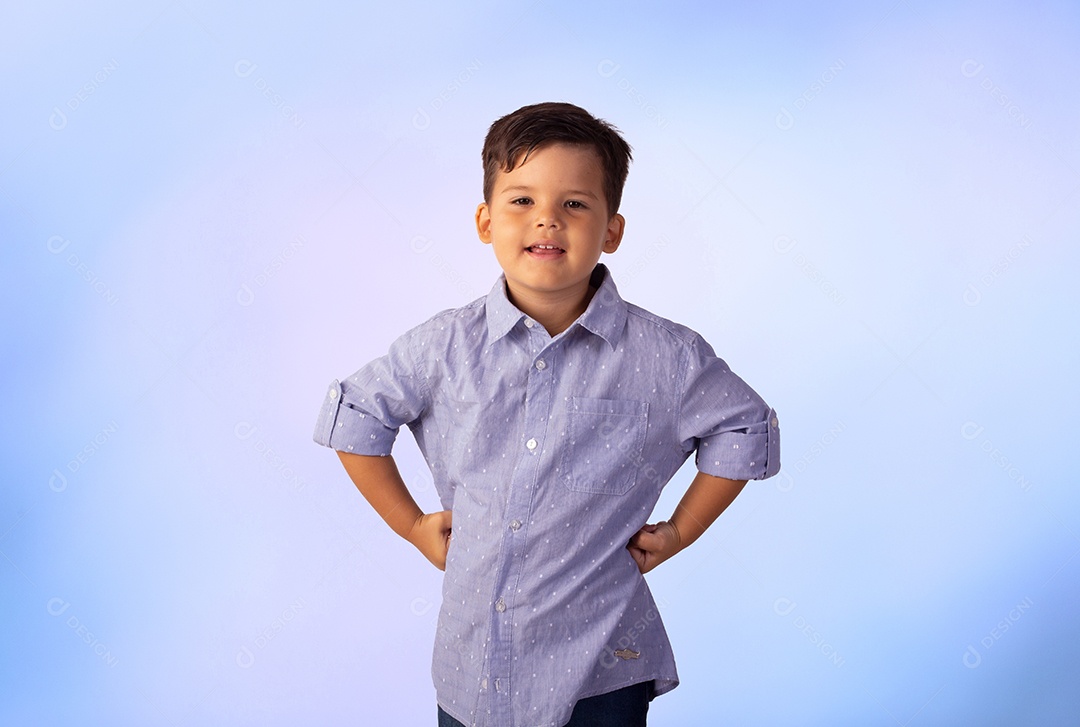Criança do sexo masculino em foto de estúdio com fundo azul vestindo camisa e jeans