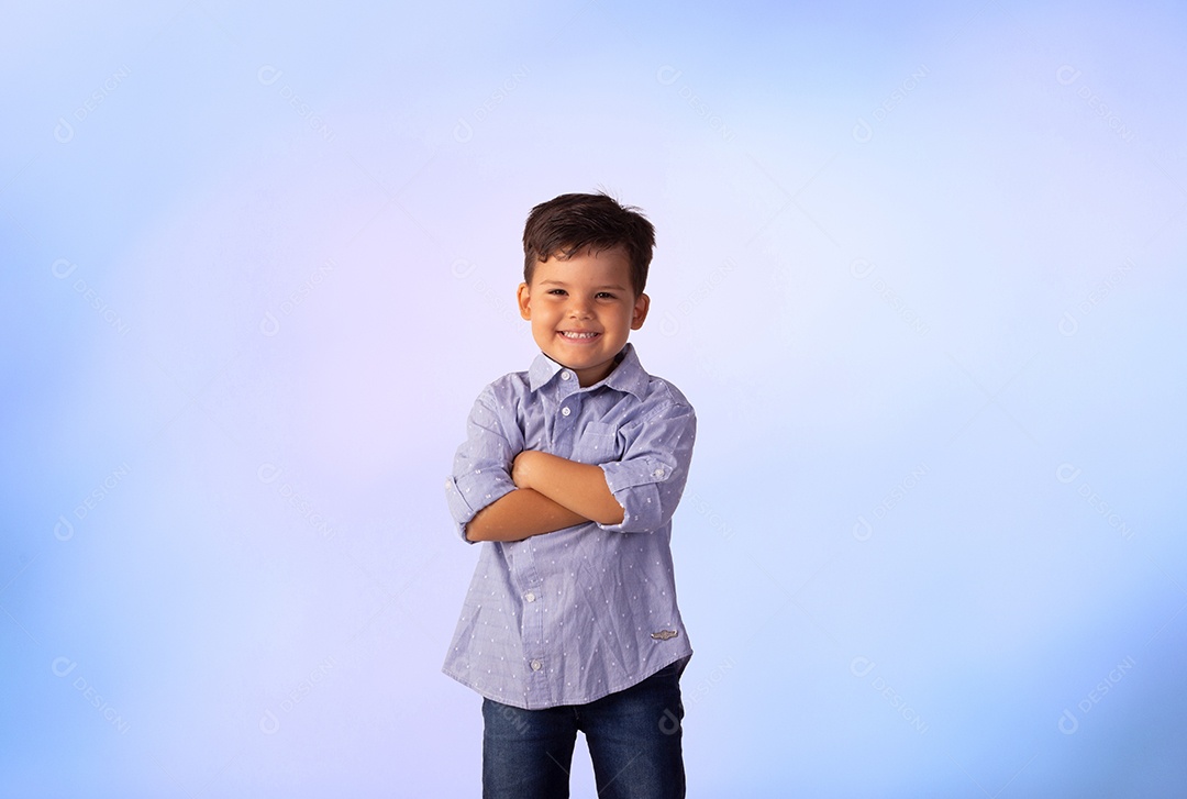 Criança do sexo masculino em foto de estúdio com fundo azul vestindo camisa e jeans