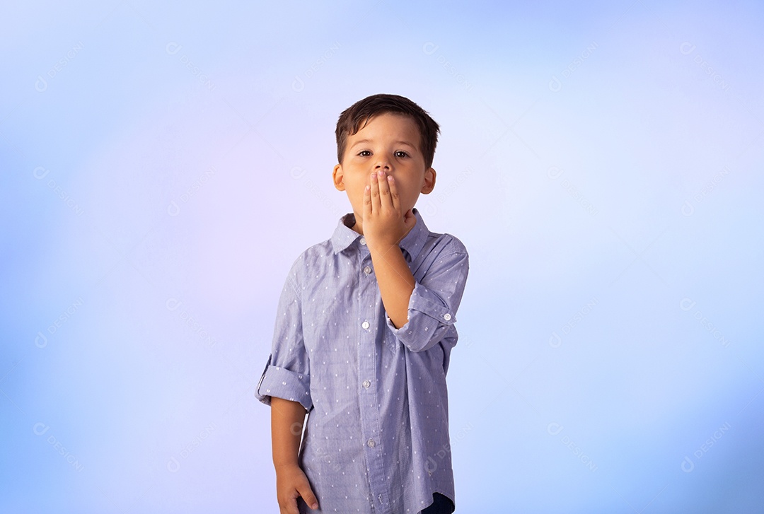 Criança do sexo masculino em foto de estúdio com fundo azul vestindo camisa e jeans