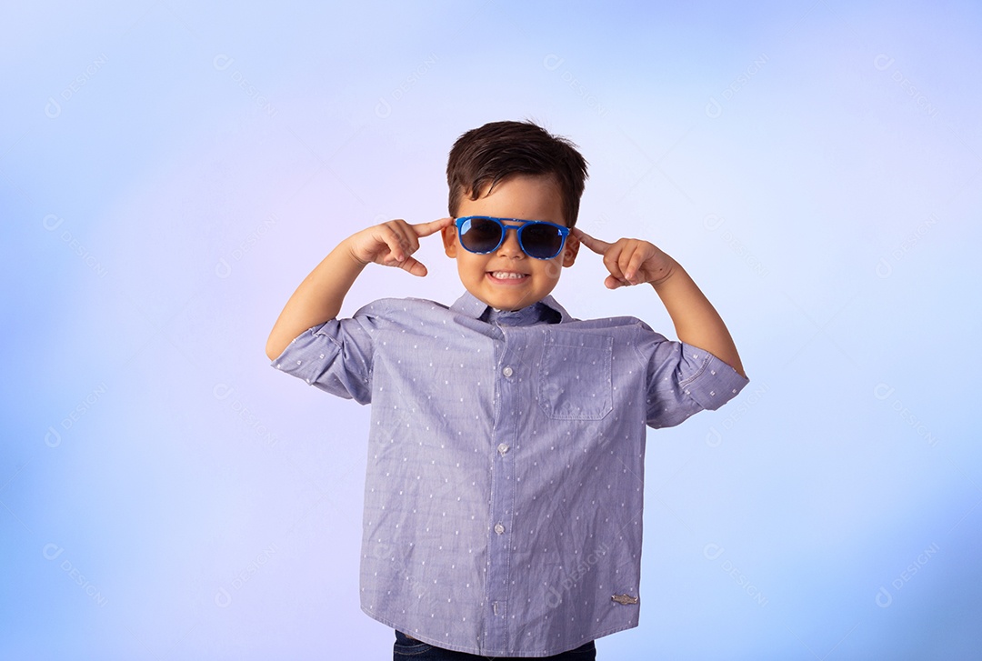 Criança do sexo masculino em foto de estúdio com fundo azul vestindo camisa e jeans