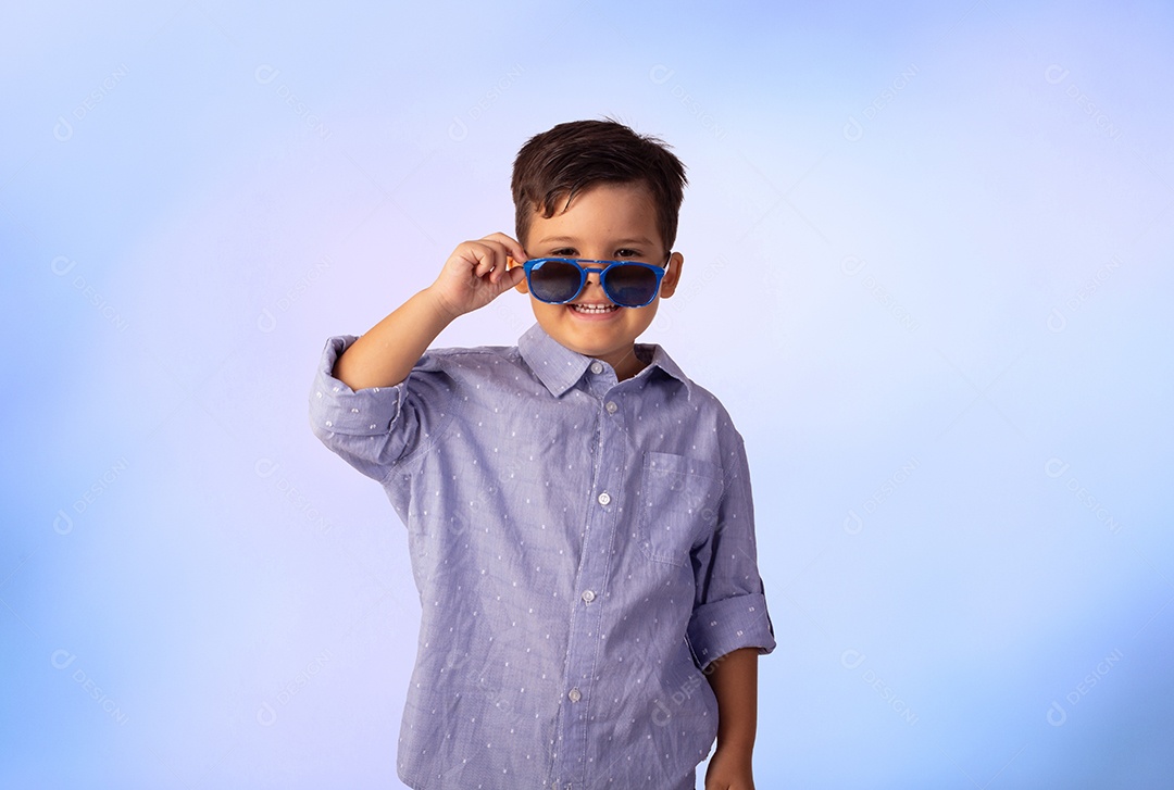 Criança do sexo masculino em foto de estúdio com fundo azul vestindo camisa e jeans
