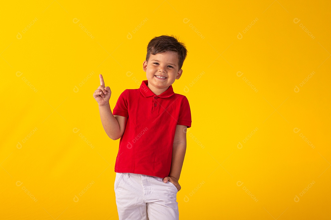 Criança do sexo masculino em foto de estúdio com fundo claro vestindo camisa e jeans