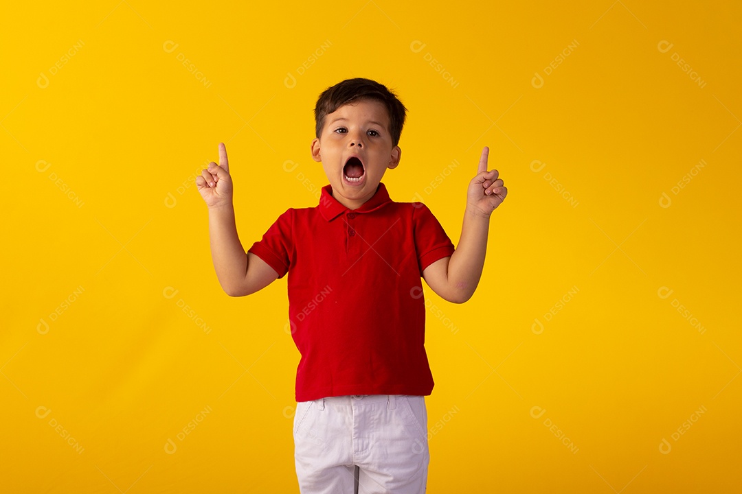 Criança do sexo masculino em foto de estúdio com fundo amarelo vestindo camisa e jeans