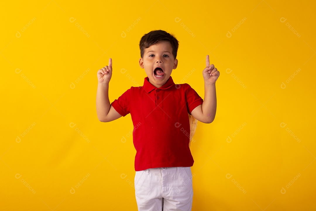 Criança do sexo masculino em foto de estúdio com fundo amarelo vestindo camisa e jeans