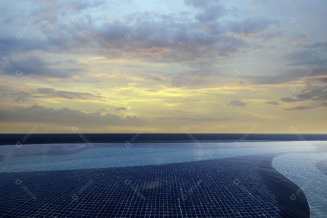 Piscina de borda infinita ao pôr do sol com vista serena para o oceano e céu colorido