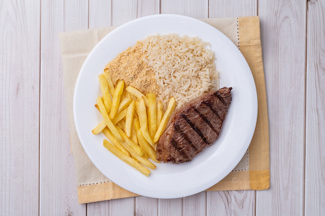 A imagem mostra um prato de comida que inclui um bife, batatas fritas, arroz e feijão
