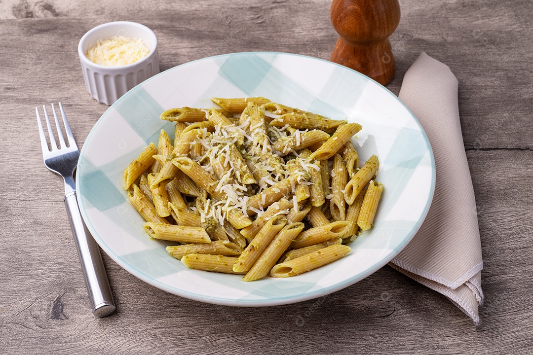 A imagem mostra um prato de massa (penne) com molho pesto