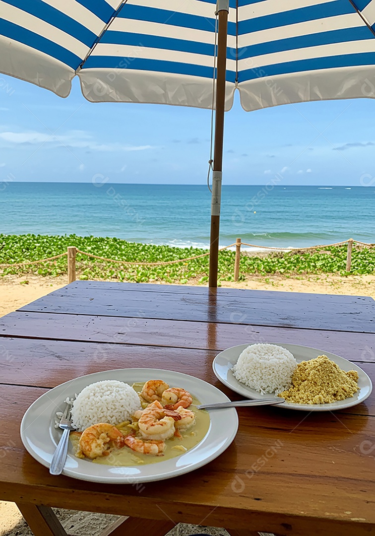 Belo camarão ao molho sobre mesa de madeira em uma linda praia