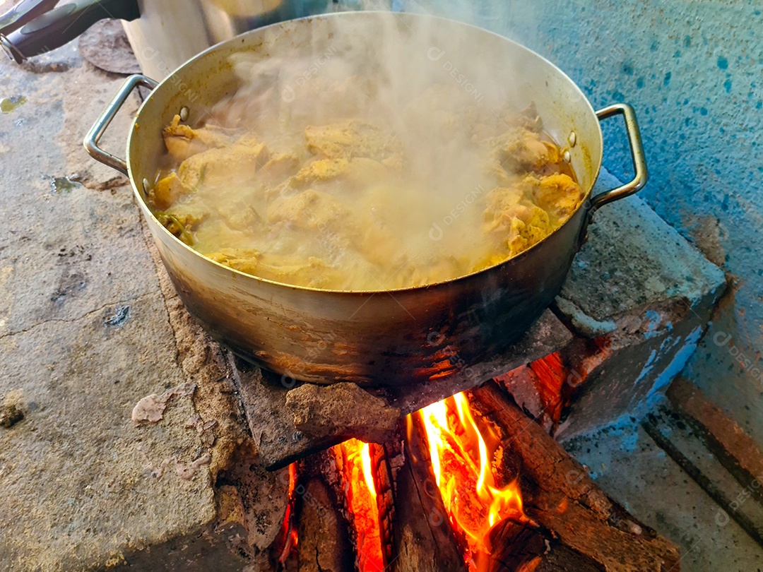 Galinha cozinhando na panela em fogão caipira