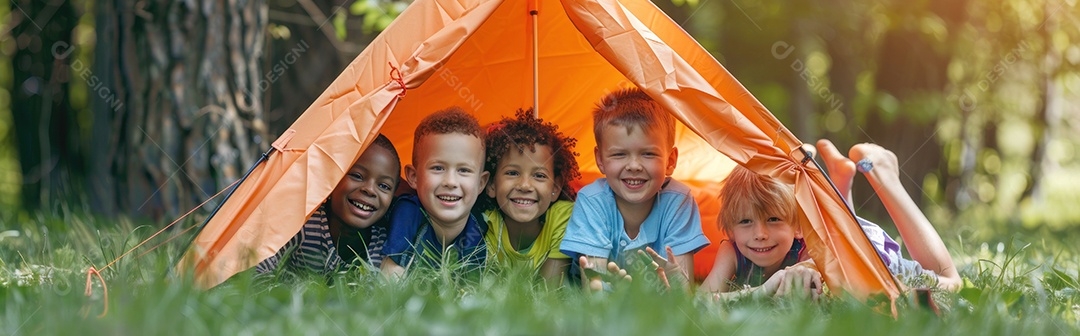 Foto panorâmica de crianças multiculturais felizes sorrindo enquanto estão deitadas perto do acampamento