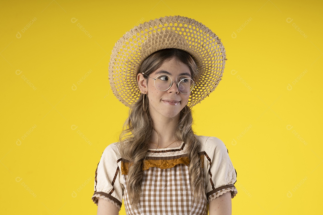 Mulher jovem usando roupas tipicas de festa junina e usando um chapéu de palha