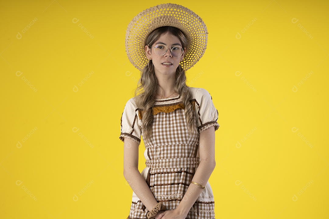 Jovem garota usando roupas tipicas de festa junina e usando chapéu de palha e com óculos