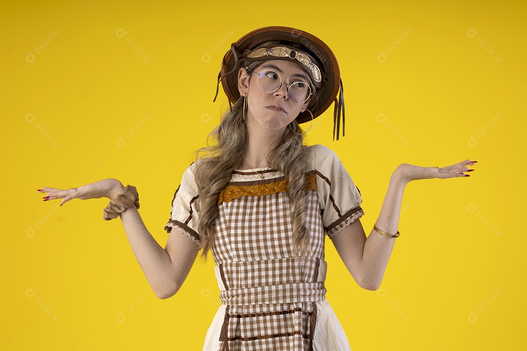 Jovem com gesto de mãos para o lado e trajes juninos típicos de são joão