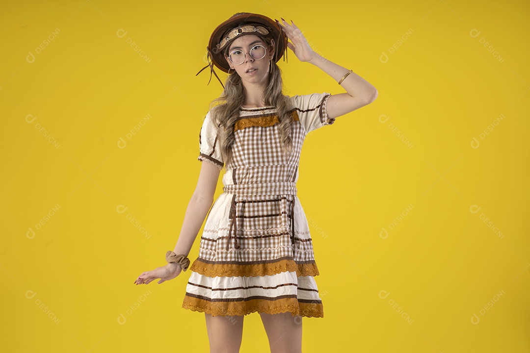 Jovem seria com trajes junino sobre fundo amarelo
