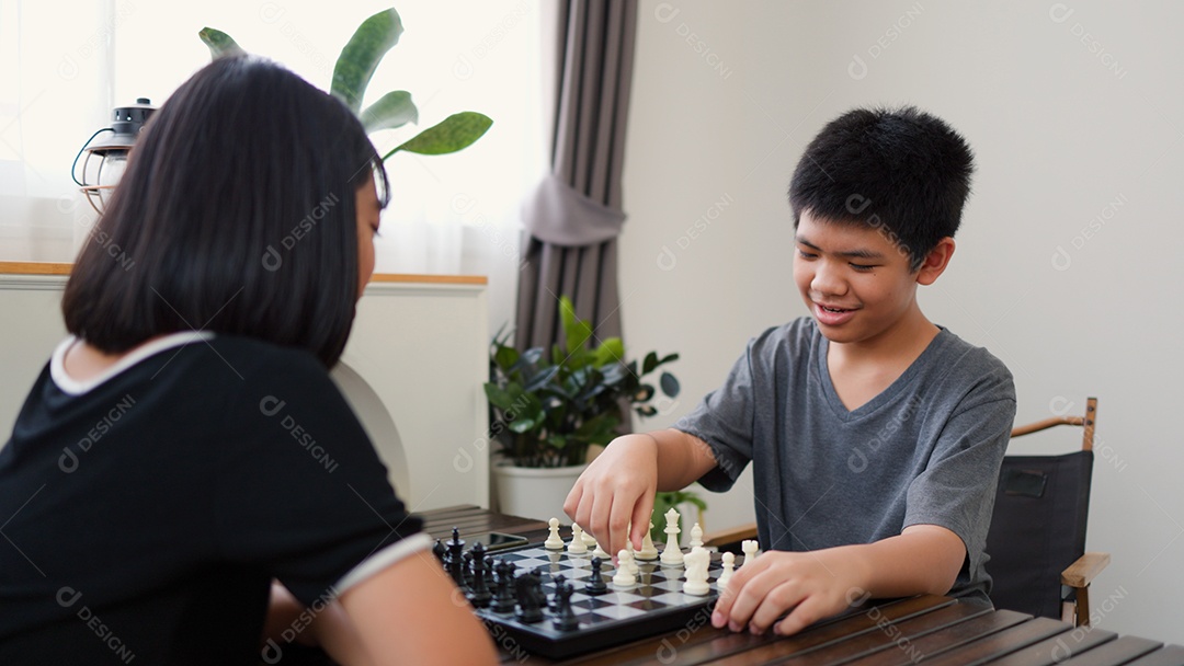 Adolescentes asiáticos jogando xadrez em casa
