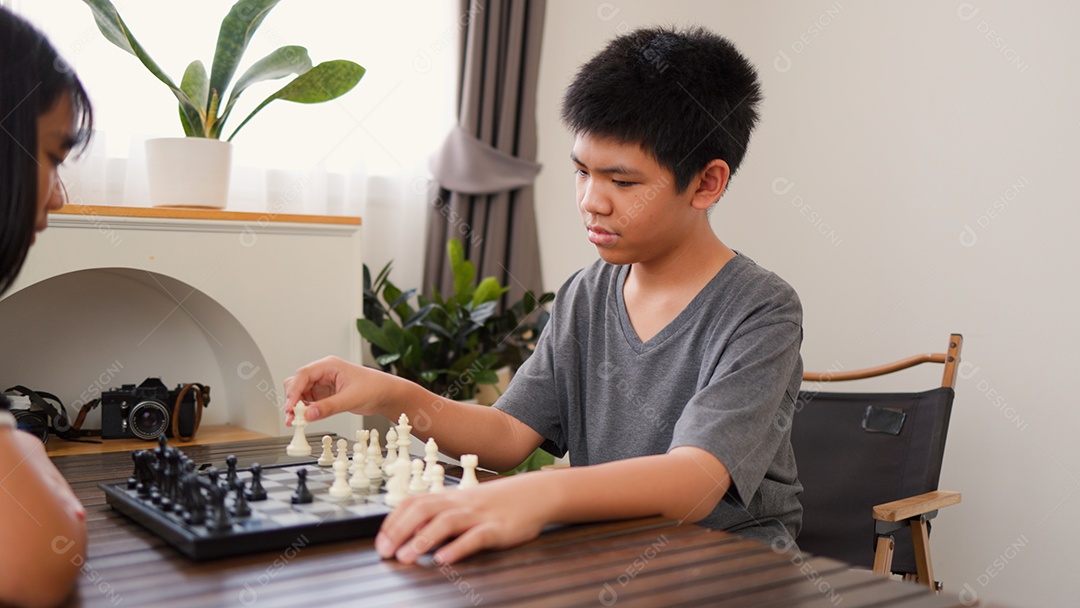 Adolescentes asiáticos jogando xadrez em casa