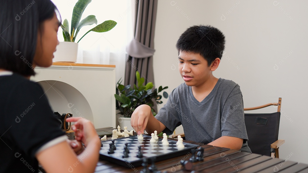 Adolescentes asiáticos jogando xadrez em casa