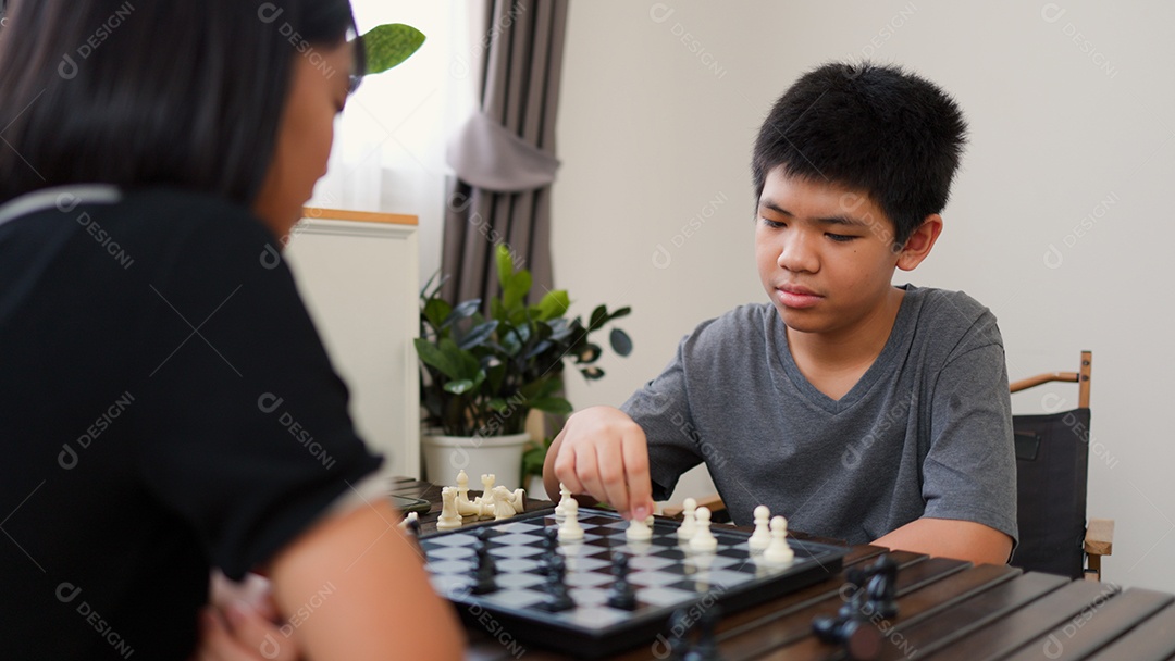 Adolescentes asiáticos jogando xadrez em casa