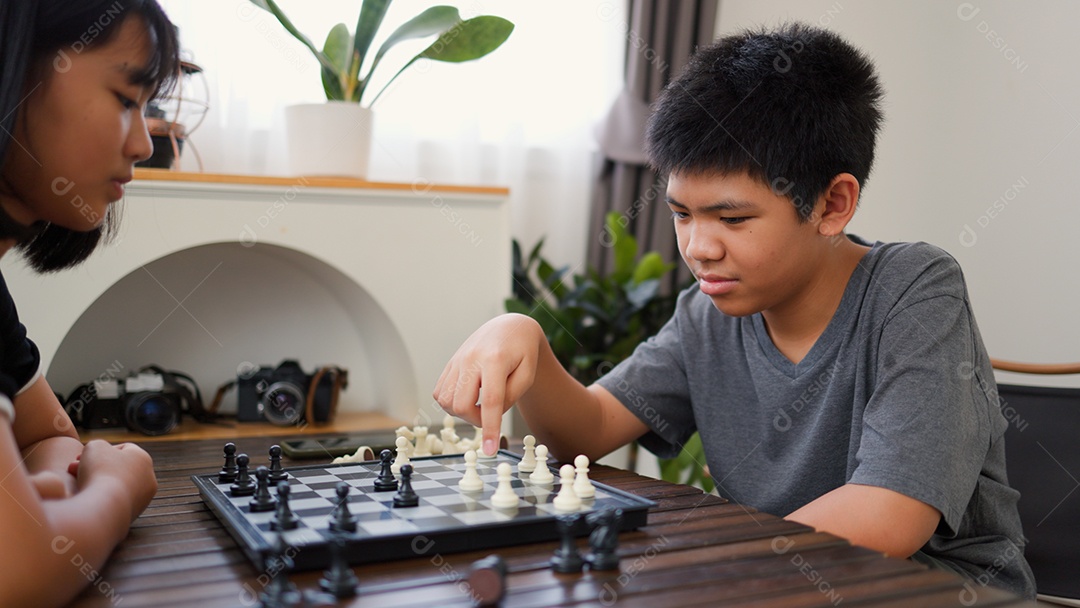 Adolescentes asiáticos jogando xadrez em casa