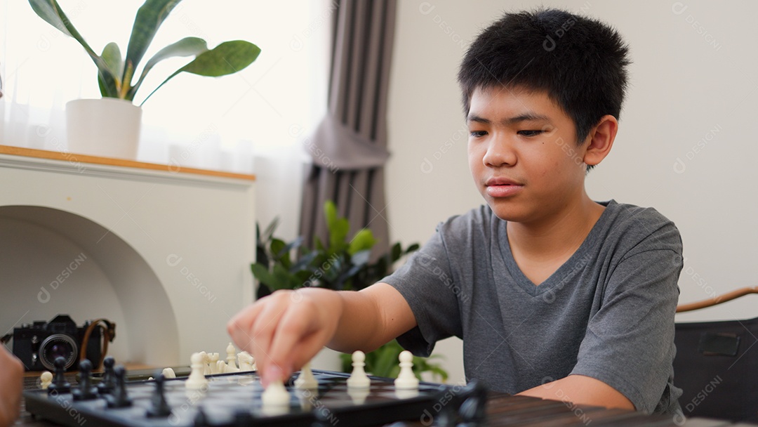 Adolescentes asiáticos jogando xadrez em casa