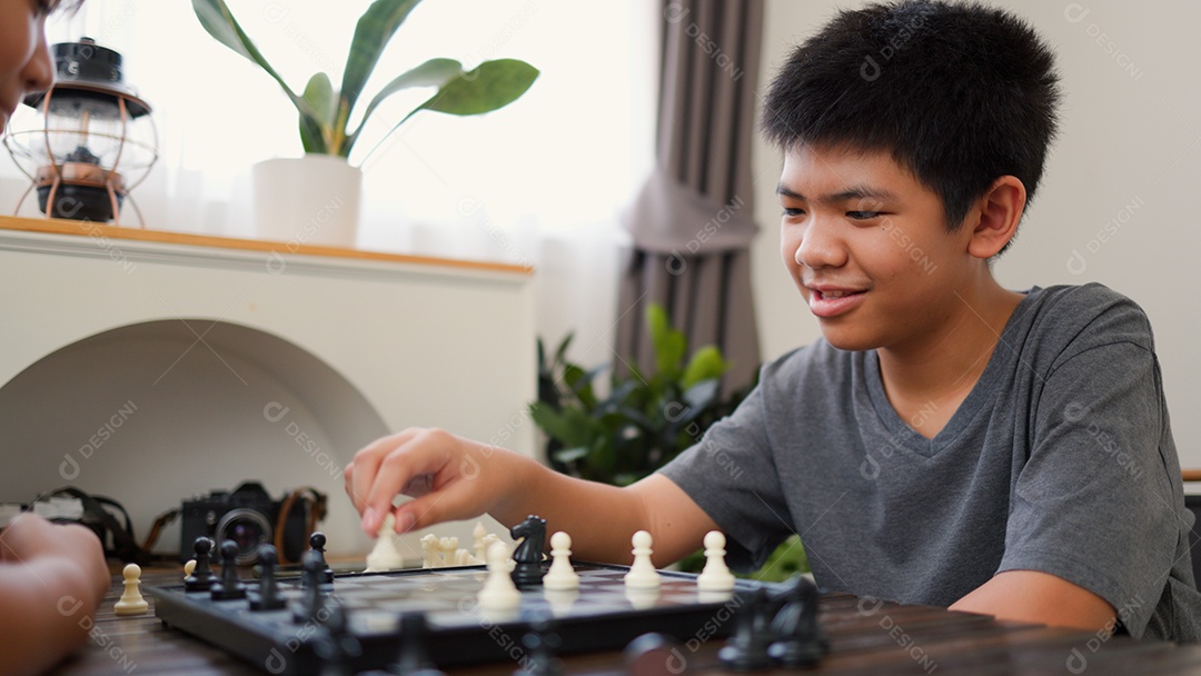 Adolescentes asiáticos jogando xadrez em casa