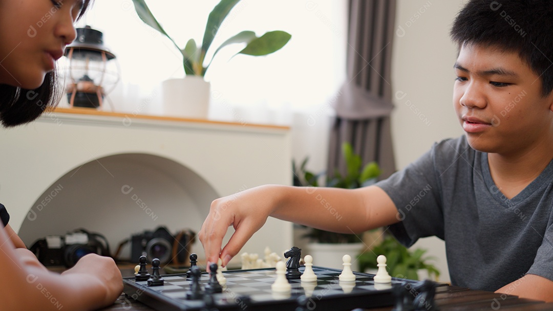 Adolescentes asiáticos jogando xadrez em casa