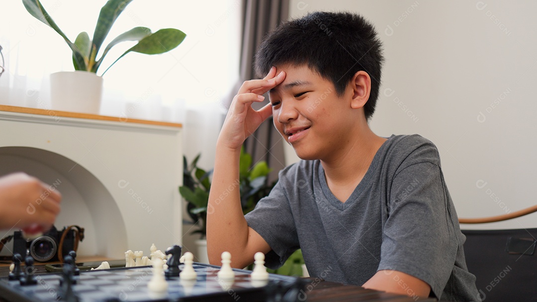 Adolescentes asiáticos jogando xadrez em casa