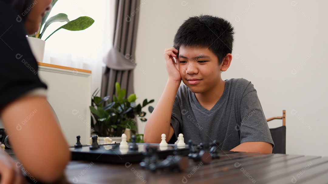 Adolescentes asiáticos jogando xadrez em casa