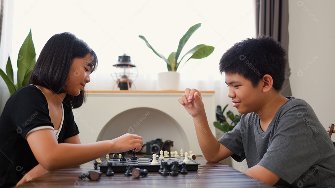 Adolescentes asiáticos jogando xadrez em casa