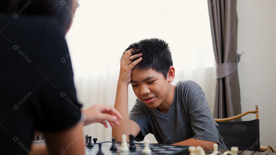 Adolescentes asiáticos jogando xadrez em casa