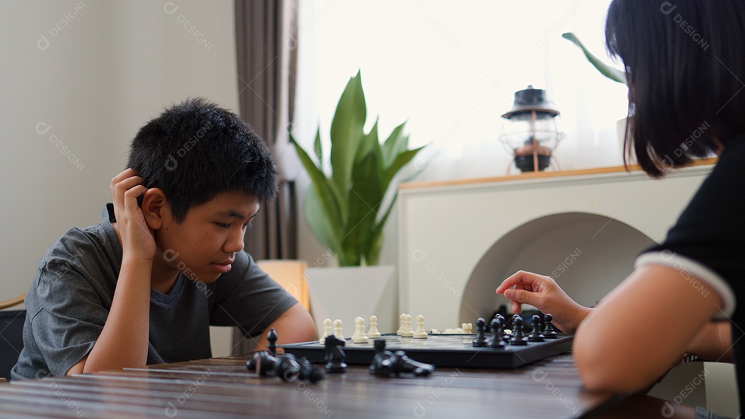 Adolescentes asiáticos jogando xadrez em casa