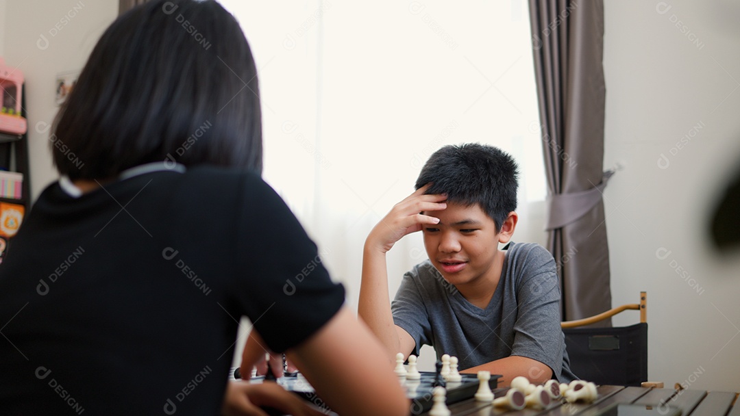 Adolescentes asiáticos jogando xadrez em casa