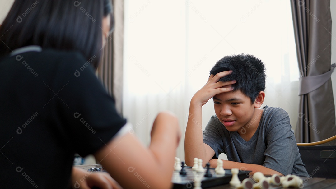 Adolescentes asiáticos jogando xadrez em casa