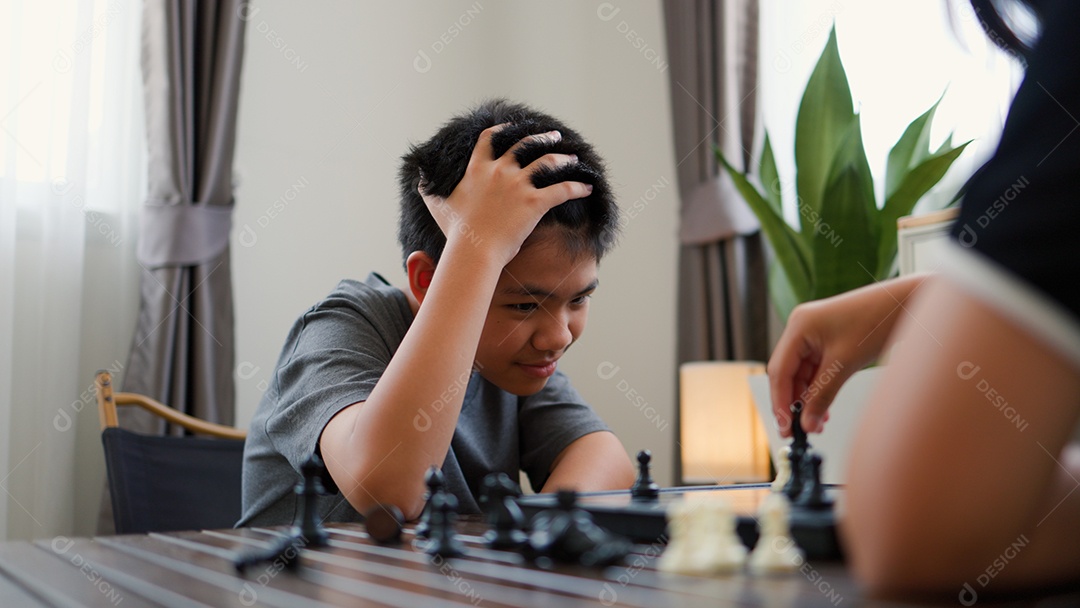 Adolescentes asiáticos jogando xadrez em casa