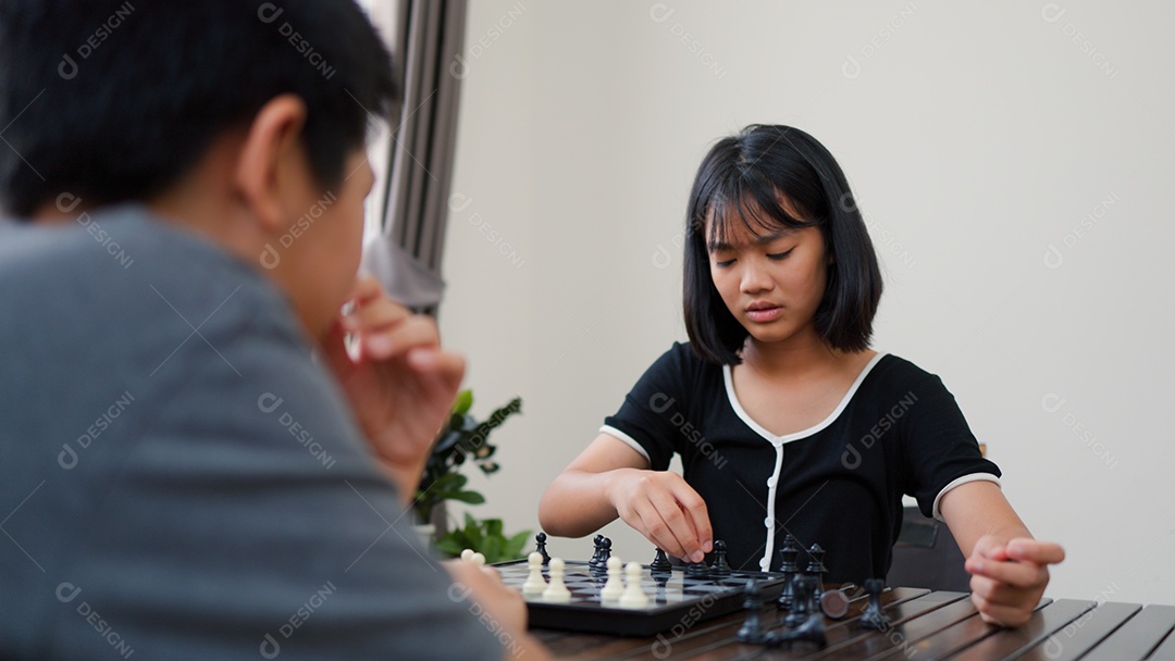 Adolescentes asiáticos jogando xadrez em casa