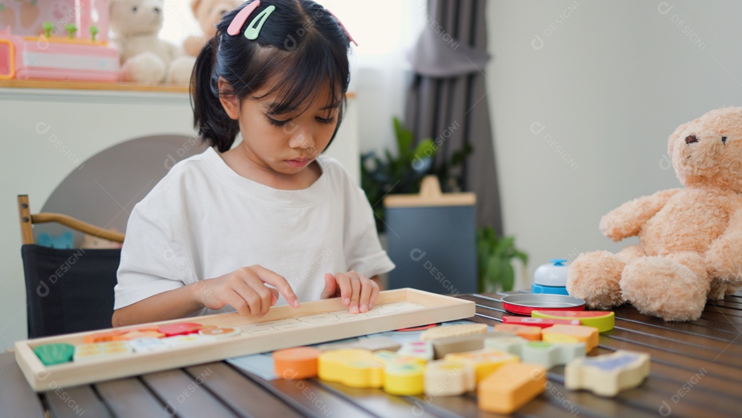 Menina asiática brincando com blocos de quebra-cabeça coloridos em casa