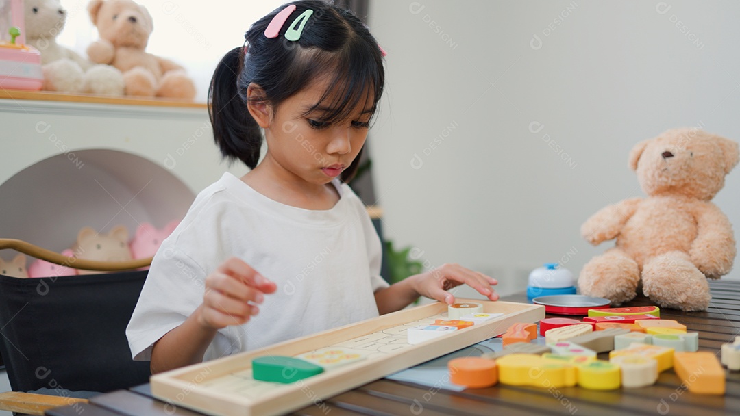 Menina asiática brincando com blocos de quebra-cabeça coloridos em casa
