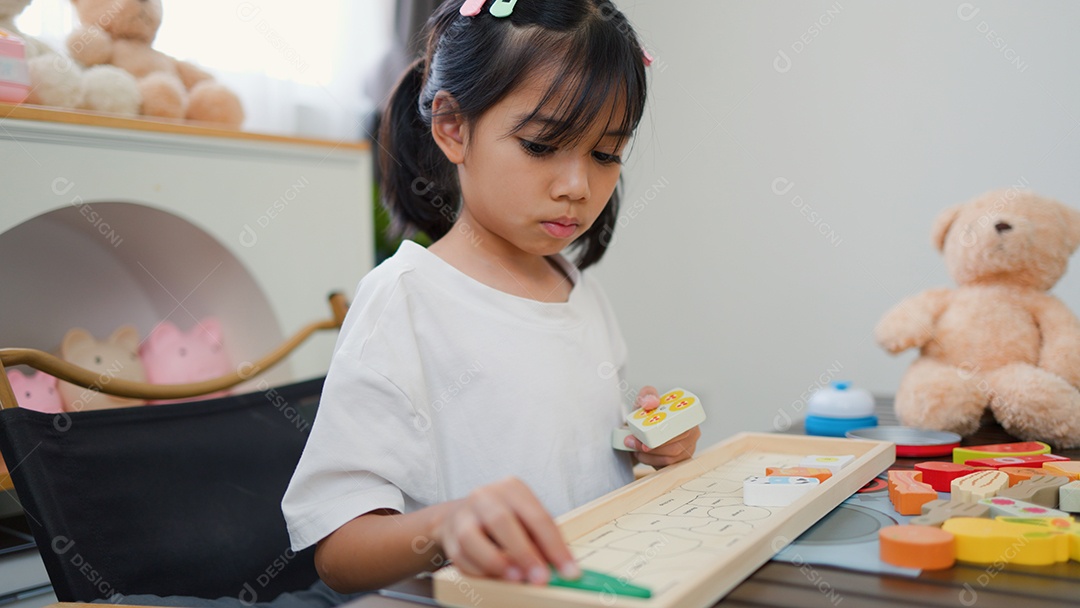 Menina asiática brincando com blocos de quebra-cabeça coloridos em casa