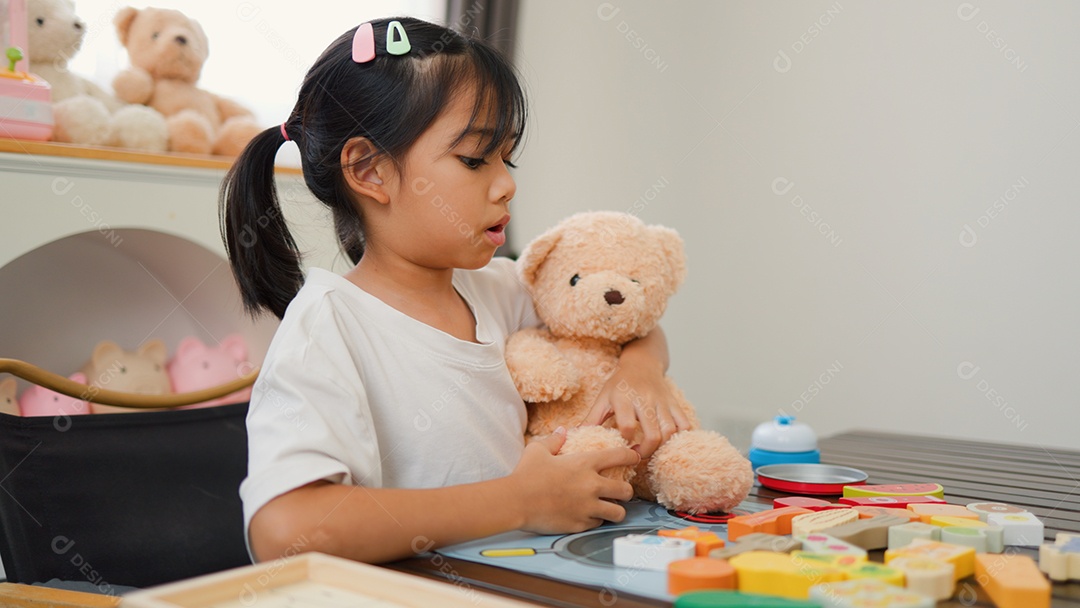 Menina asiática brincando com blocos de quebra-cabeça coloridos em casa